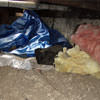 A crawl space filled with loose insulation, debris, and a large tarp in Libertyville.